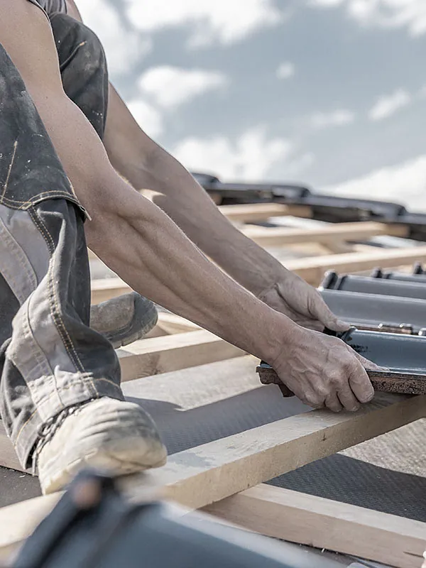 Dachdecker platziert Dachschindel auf Dachgerüst
