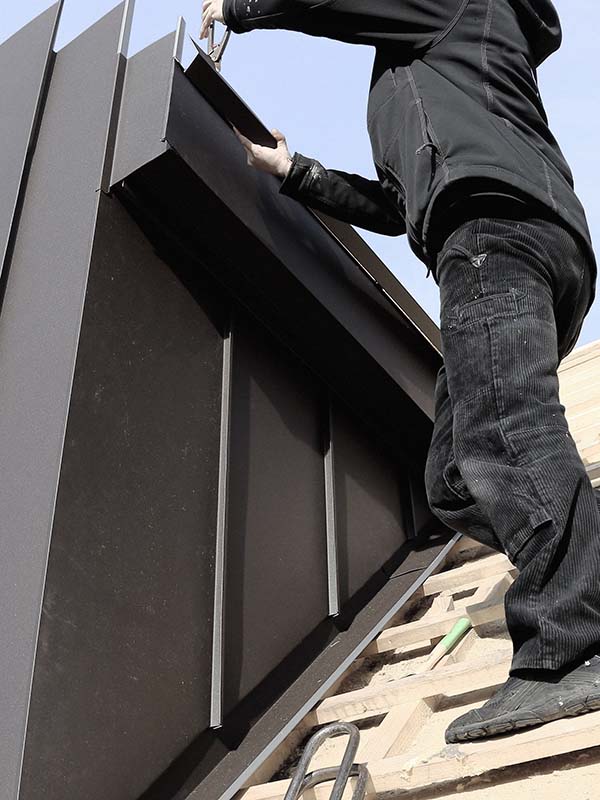 Sprengler arbeitet mit Metallplatten auf Dach